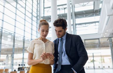 vrouw en man kijken op smartphone in kantooromgeving