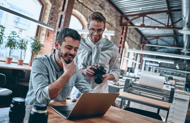 Twee mannen kijken naar een foto op een laptop